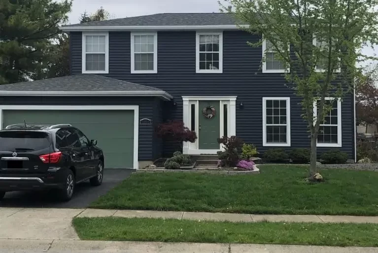 Blue house with new siding, green windows, and doors