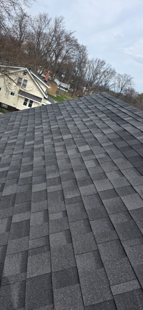 Close-up view of freshly installed dark grey architectural roof shingles.